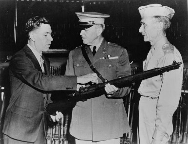 Garand showing his rifle design to two military officers.