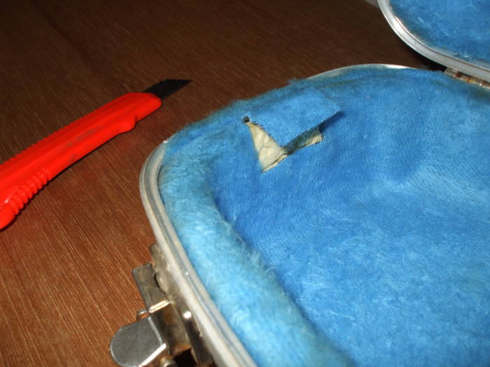 Cutting blue fur from the interior of a guitar case.