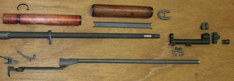 disassembled M1 Garand showing relationship of parts, especially the barrel, operating rod, and gas cylinder assembly.